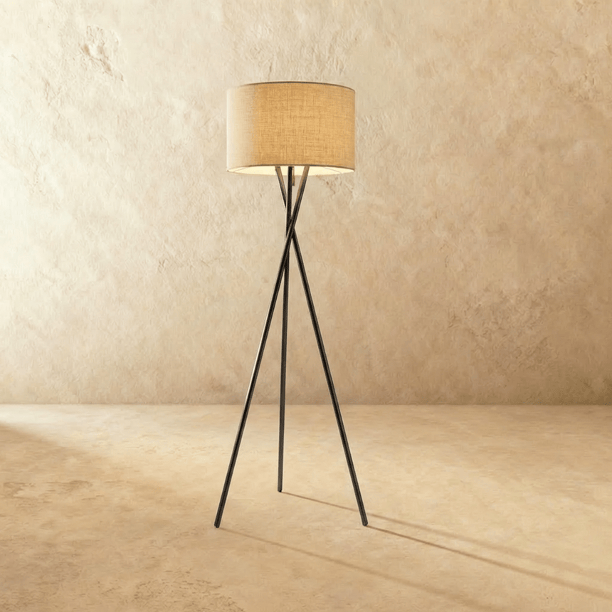 The tripod with a natural weave drum shade above its three crossing legs