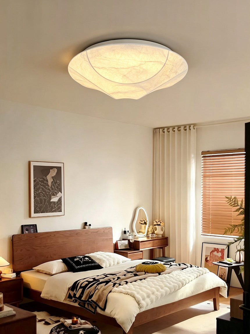 Round silk ceiling light in a bedroom with a wood bed and a dressing table