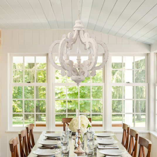 Chandelier lit above a set dining table in a room with tall windows