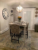 Chandelier lit in a hallway above a rug and a wall clock