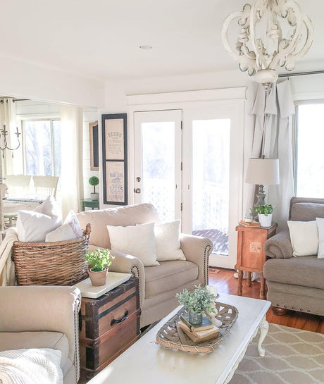 Chandelier lit in a living room above a pale sofa and a chest
