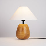 Farmhouse table lamp lit on a nightstand in a warm bedroom at night
