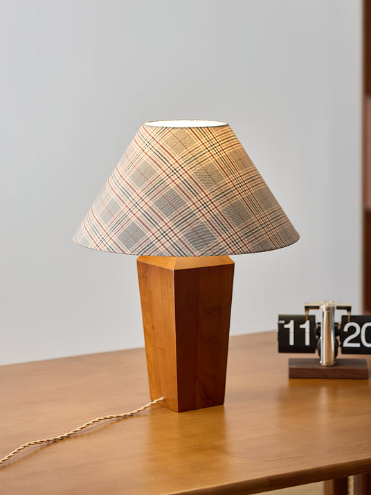 Plaid shade lamp lit on a wood desk beside a flip calendar