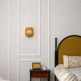 The hemp lamp lit on a paneled wall above a nightstand beside a bed