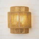 The two tier hemp shade lit, the rope strands and the bulb glow visible