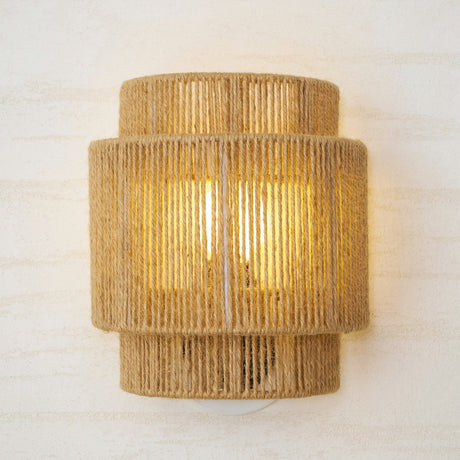 The two tier hemp shade lit, the rope strands and the bulb glow visible