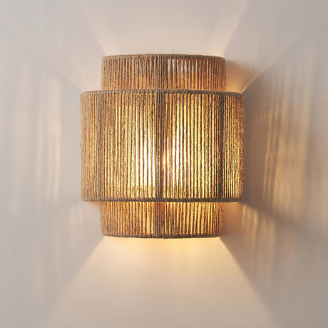 The hemp lamp lit on a pale wall, light washing up and down from the tiers