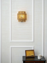 The hemp lamp on a white paneled wall above a small dark nightstand
