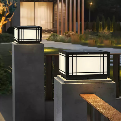 The lantern lit on a pillar beside a timber bench in a dark garden