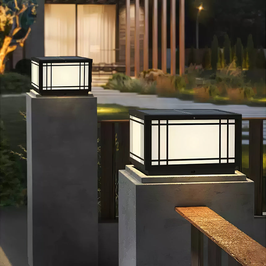 The lantern lit on a pillar beside a timber bench in a dark garden