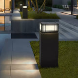 Two lanterns lit on low pillars at the edge of a lawn at night