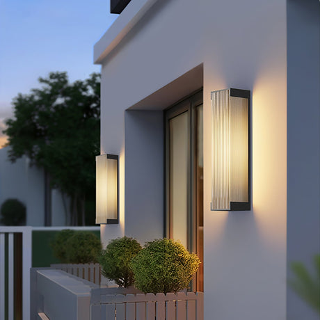 The sconce lit beside an entry doorway with a plant in a tall pot