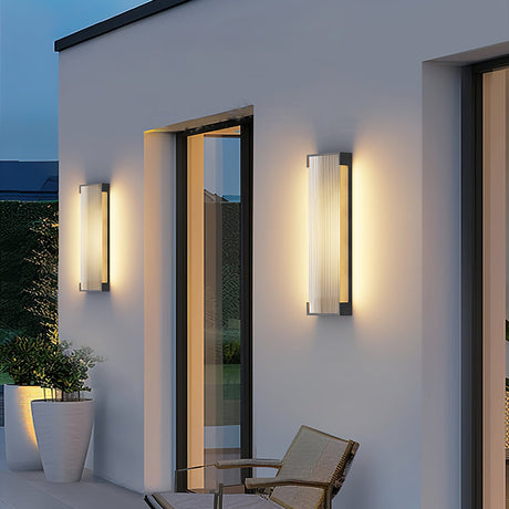 The sconce lit beside glass doors on a terrace with a woven chair