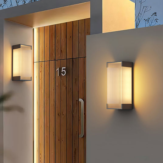 Two lit either side of a timber front door with a house number on it