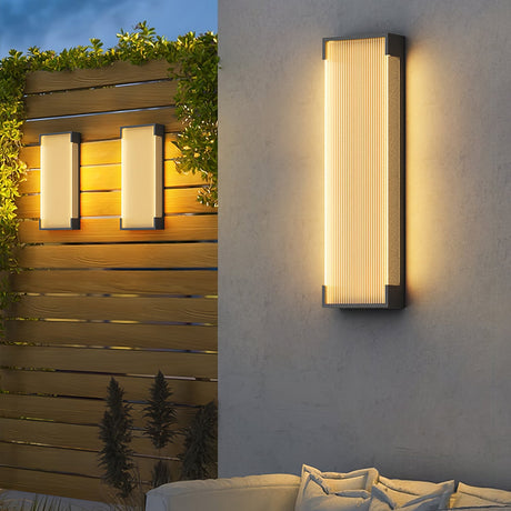 A pair lit on a timber screen behind a garden sofa with cushions