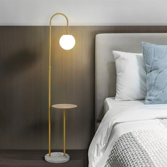The lit globe beside a bed with pillows and a padded headboard in a bedroom