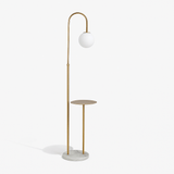 A gold stem with a hooked top and a glass globe above a round wooden tray table