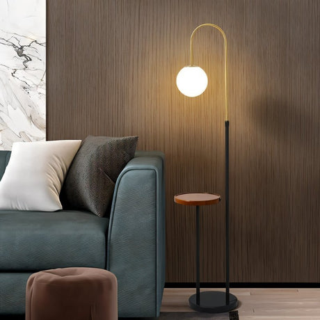 The black version lit beside a teal sofa and a marble wall with a stool