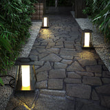 Two lit along a flagstone path with dark planting behind them