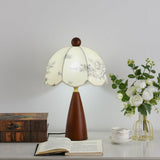 Floral table lamp lit beside a glass vase of white roses