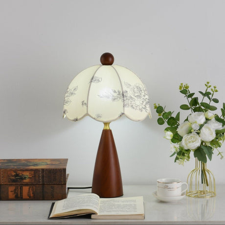 Floral table lamp lit beside a glass vase of white roses
