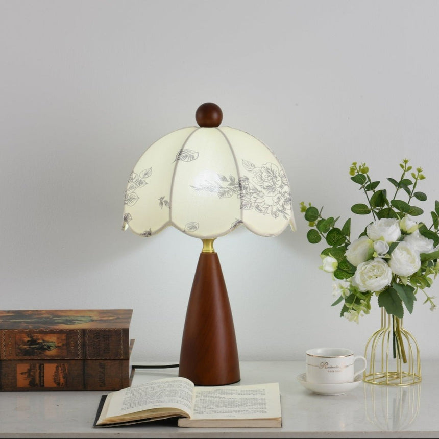 Floral table lamp lit beside a glass vase of white roses