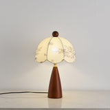 Full view of the floral table lamp lit against a pale ground