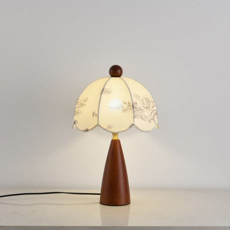 Full view of the floral table lamp lit against a pale ground