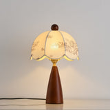 Floral table lamp lit against a plain pale ground