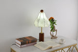 Parasol shade lamp lit with a cooler bulb on a pale desk