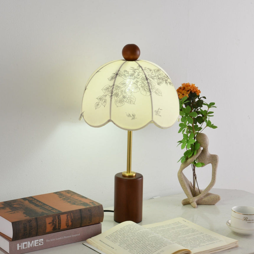 Parasol shade lamp lit warm beside a sculpture and orange flowers