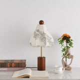 Taller bell shaped shade lit warm beside a stack of books