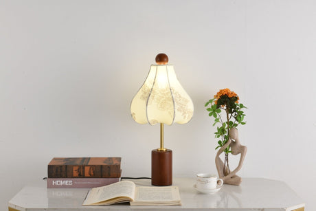 Parasol shade lamp unlit on a white desk beside bound books