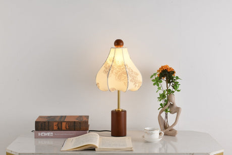 Parasol shade lamp lit beside a small plant and a bound book