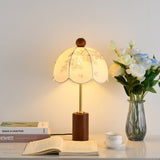 Parasol shade lamp lit beside a glass vase of cream roses