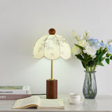 Parasol shade lamp unlit beside white roses in a glass vase