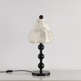 Black floral table lamp seen from an angle with the cord switch visible