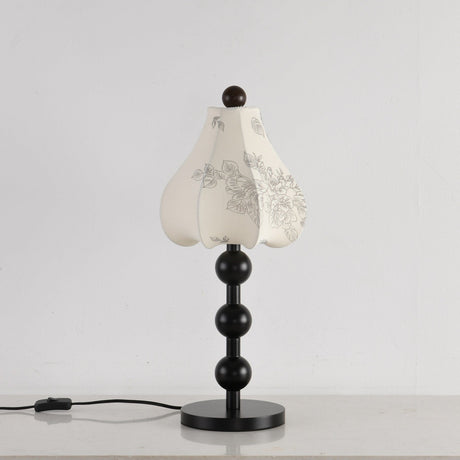 Black floral table lamp seen from an angle with the cord switch visible