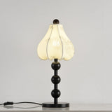 Black floral table lamp lit, the petal shade glowing warm from inside