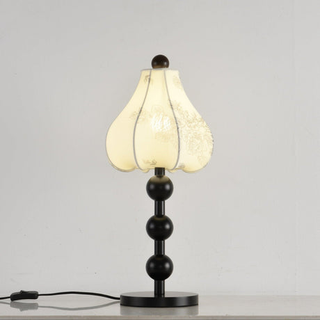 Black floral table lamp lit, the petal shade glowing warm from inside