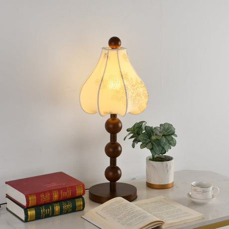 Close view of the walnut lamp lit, the petals glowing above the spheres