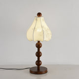 Walnut floral table lamp lit, the ribs of the petal shade showing through
