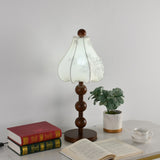 Walnut floral table lamp unlit beside a small plant and a stack of books