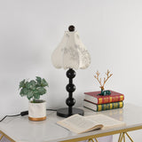 Floral table lamp on a console beside a small decorative brass branch