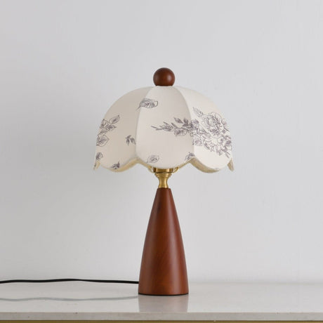 Floral table lamp unlit on a plain ground with the cord visible
