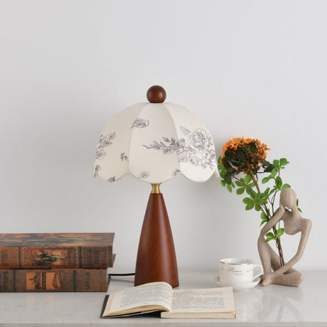 Floral table lamp unlit beside a pale figurine and sunflowers