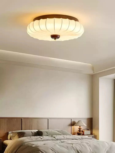 Pleated petal ceiling light in a bedroom with a low upholstered headboard