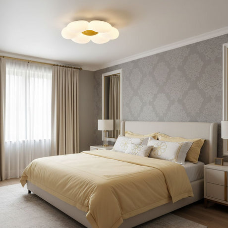 Flower ceiling light with a yellow center above a bed with beige covers