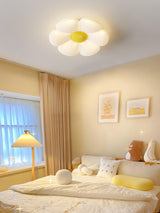 Flower ceiling light with a yellow center above a bed with yellow pillows