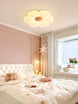 Flower ceiling light with a pink center above a bed with a tufted headboard